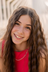 Obraz premium beautiful teenage brunette girl with long hair, smiling, looking at the camera during a summer walk