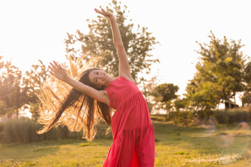 beautiful teenage brunette girl with long hair, smiling, looking at the camera during a summer walk