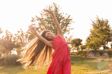 beautiful teenage brunette girl with long hair, smiling, looking at the camera during a summer walk