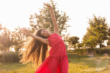 beautiful teenage brunette girl with long hair, smiling, looking at the camera during a summer walk