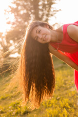 beautiful teenage brunette girl with long hair, smiling, looking at the camera during a summer walk