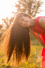 beautiful teenage brunette girl with long hair, smiling, looking at the camera during a summer walk