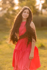 beautiful teenage brunette girl with long hair, smiling, looking at the camera during a summer walk