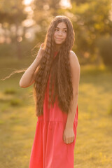 beautiful teenage brunette girl with long hair, smiling, looking at the camera during a summer walk