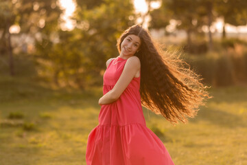 beautiful teenage brunette girl with long hair, smiling, looking at the camera during a summer walk