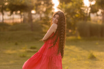 beautiful teenage brunette girl with long hair, smiling, looking at the camera during a summer walk