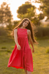 beautiful teenage brunette girl with long hair, smiling, looking at the camera during a summer walk