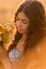 beautiful teenage brunette girl with long hair, smiling, looking at the camera during a summer walk