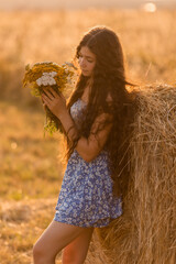 beautiful teenage brunette girl with long hair, smiling, looking at the camera during a summer walk