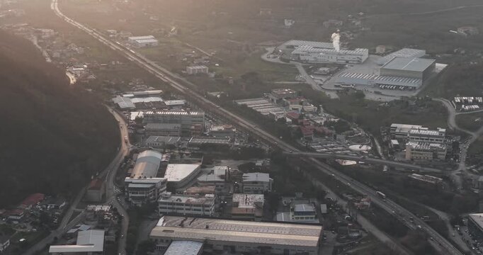 Aerial view of industrial tanning factory buildings, roads, and greenery blending under a hazy sky, creating a textured landscape, Solofra, Campania, Italy.