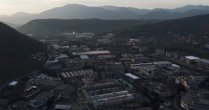 Aerial view of tanning factory buildings nestled against a backdrop of rolling mountains, a blend of urban and natural beauty, Solofra, Campania, Italy.