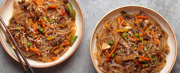 Two bowls of japchae, korean glass noodles stir fry with vegetables and mushrooms