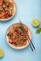 Two bowls of vegetarian udon noodles with fried tofu and vegetables is served with chopsticks