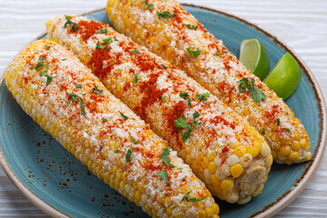 Delicious Mexican dish Elotes corn cob covered in spices and cheese