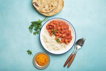 Indian chicken curry with basmati rice served on plate with chapati flatbread on the side top view
