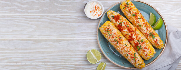Elotes mexican street corn cob covered in spices and cheese being served on plate