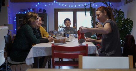 A domestic scene showing a woman pouring fresh coffee into a red cup at breakfast time.