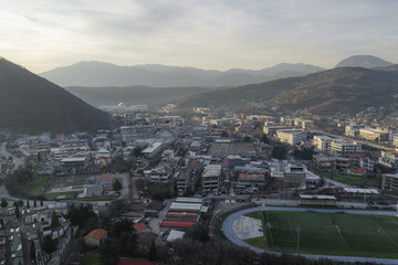 Aerial view of a landscape where tanning factory buildings nestle among the hills, with a stadium adding a vibrant green touch to the scene, Solofra, Campania, Italy.