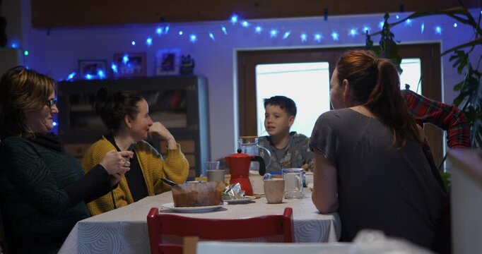 During a morning gathering in the dining room, the family group use a smartphone to read their secret roles for the impostor game.