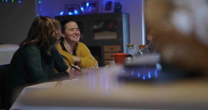 Two women enjoy a fun morning playing the impostor game on their phones while having breakfast in a cozy, natural home setting.