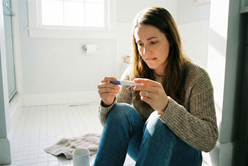 Young woman reacting to pregnancy test results in a bright bathroom