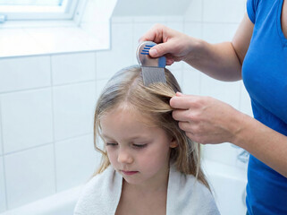 A young girl having her hair combed by an adult in a bathroom with white tiles and a window
