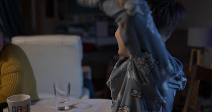 The boy reacts dramatically, laughing, when he is discovered or loses the game.
