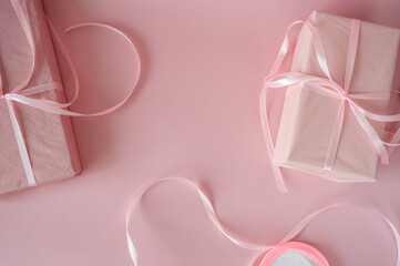 Top view of pink gift boxes with satin ribbons on a pink background. Minimalist feminine flat lay with copy space for Valentine's Day, Birthday or Mother's Day