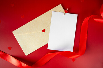 Valentine's Day mockup with blank white card, craft envelope with red heart, and silk ribbon on red background