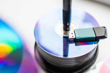 Bunch of CD and DVD discs with USB flash drive placed on them.