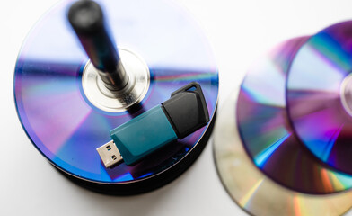 Bunch of CD and DVD discs with USB flash drive placed on them.
