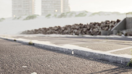 Soft waves lap at the shore as morning light reflects off the pavement. Tall buildings rise in the background, creating a serene and peaceful environment at the beach.