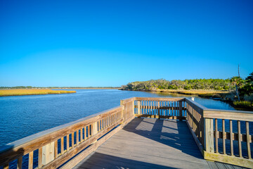 Obraz premium Wooden Deck Over Calm Water with Clear Blue Sky