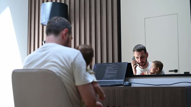 Multitasking parent holding a child on his lap while working on a laptop computer and talking on the phone, illustrating the challenges of balancing family life and remote work