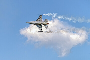 Wojskowy odrzutowy samolot myśliwski wystrzeliwujący flary podczas pokazów lotniczych © piotr