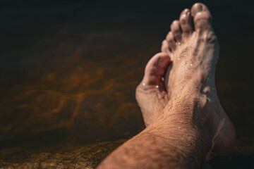 Pies de un hombre relaj&aacute;ndose en el agua, concepto de vacaciones y descanso.
