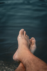 Pies de un hombre relaj&aacute;ndose en el agua, concepto de vacaciones y descanso.
