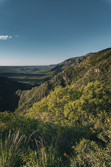 Vista panor&aacute;mica de un valle monta&ntilde;oso bajo un cielo azul despejado en hora dorada