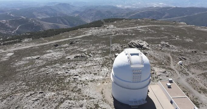 Drone aerial close-up of Calar Alto Observatory telescope dome, Tabernas Spain, white radome against barren mountain landscape and distant ranges