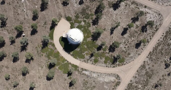 Overhead drone aerial of Calar Alto Observatory site, Tabernas Spain, dome building surrounded by sparse vegetation and mountain tracks