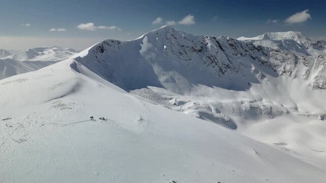 A scenic aerial view of skiers trekking through the snowy ridges of Gulmarg, Kashmir. The snow-covered peaks and vast landscapes highlight the beauty of this winter wonderland