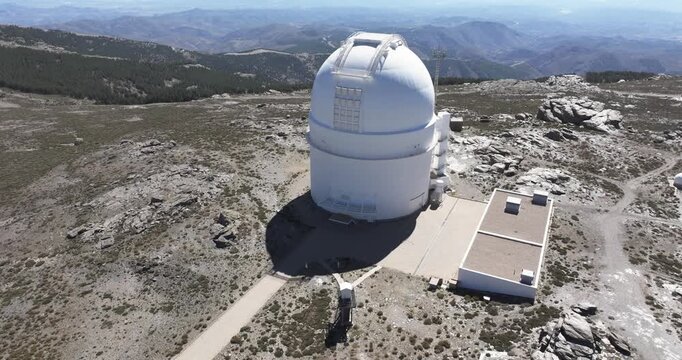 Aerial drone approach to Calar Alto Observatory main telescope dome, Tabernas Spain, white radome on barren rocky mountain landscape