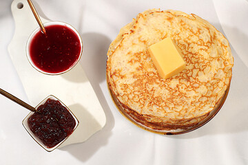 Delicious Russian pancakes with jam, preserves, and butter on a marble table. Healthy breakfast from natural ingredients, the concept of Maslenitsa and natural products 