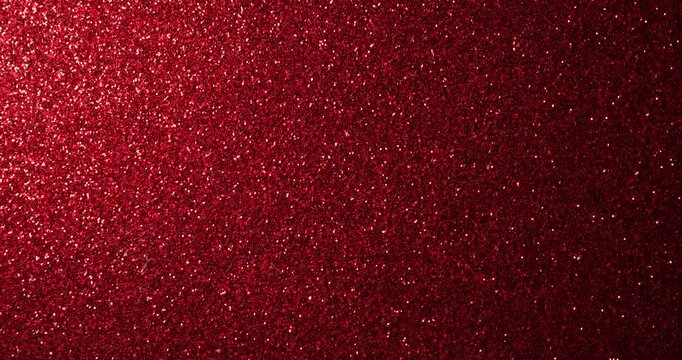 Animated stop-motion loop of red glitter surface with shimmering sparkles and light reflections, ideal for celebration and luxury themes.