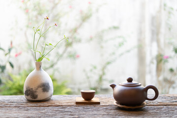 Earthenware teapot and teacup and plant pot on wood table with nature view