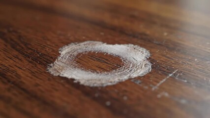Water ring marks develop on polished wooden table as cup leaves behind residue. Clear marks indicate moisture exposure on furniture. Concept of home maintenance, interior design, furniture care