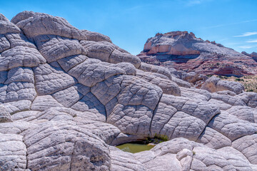 A rocky mountain with a small pool of water in the middle. The water is green and the rocks are white