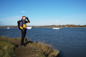Researcher Monitoring Coastal Ecosystem with Binoculars and Clipboard © Flair and Square