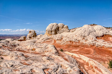 Obraz premium A rocky, barren landscape with a blue sky in the background. The rocks are white and red, and the sky is clear and bright