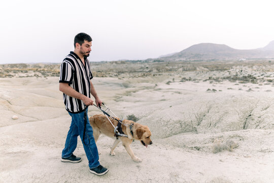 Blind man and guide dog in desert landscape